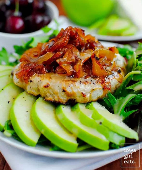 orchard turkey burger topped with caramelized onions on a salad with sliced apples