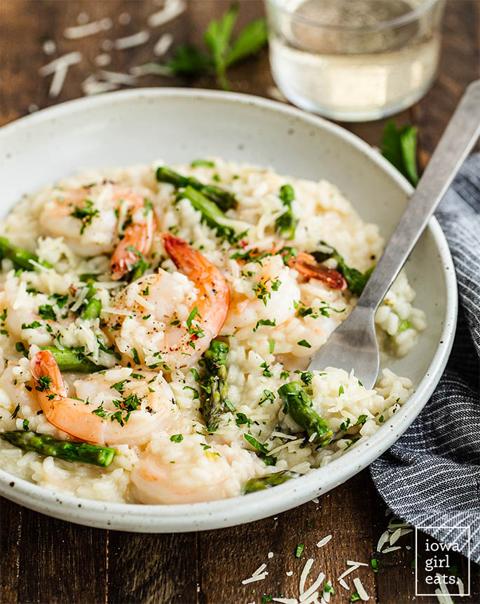 a bowl of shrimp and asparagus risotto with a spoon inside
