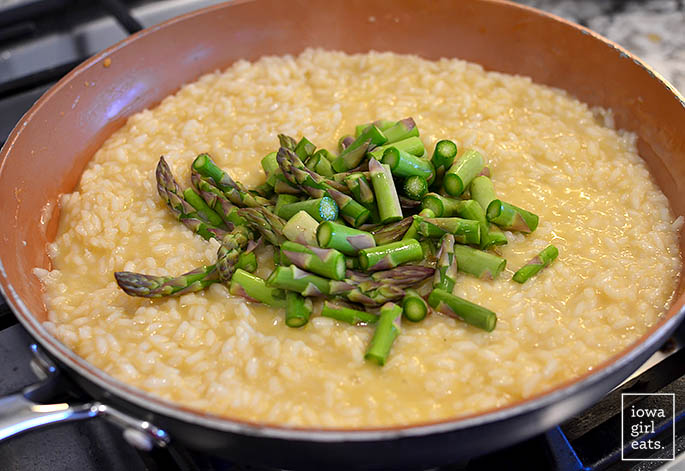 chopped asparagus being added to a skillet