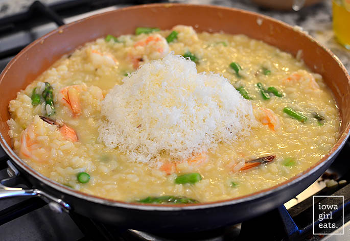 fresh parmesan cheese in a skillet of shrimp and asparagus risotto