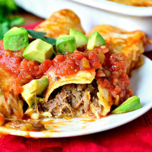 shredded beef enchiladas on a plate with salsa on top