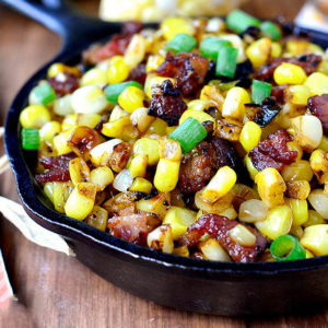 skillet full of brown butter sweet corn with maple bouron bacon