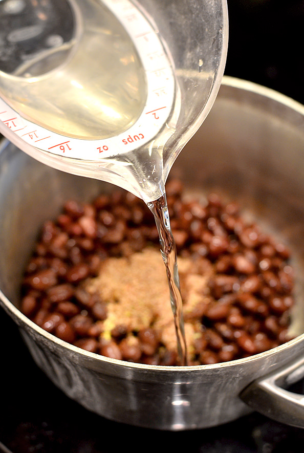 water being poured into a pot of black beans