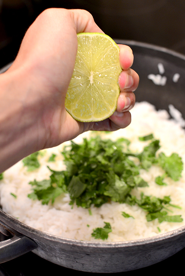 fresh lime being squeezed into a pot of cilantro lime rice