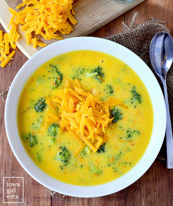 overhead photo of a bowl of broccoli cheddar soup topped with shredded cheese