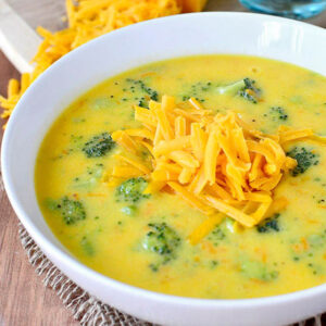 a bowl of perfect broccoli cheese soup with shredded cheese on top