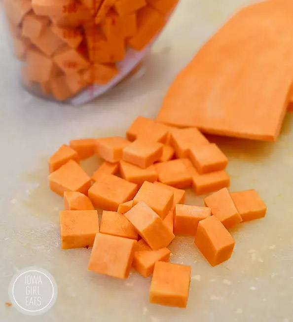 fresh sweet potatoes diced on a cutting board