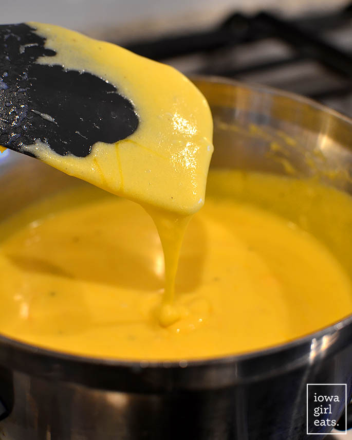 spatula drizzling with homemade cheese sauce
