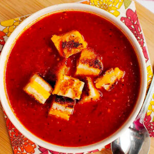 bowl of roasted tomato soup with grilled cheese croutons on top
