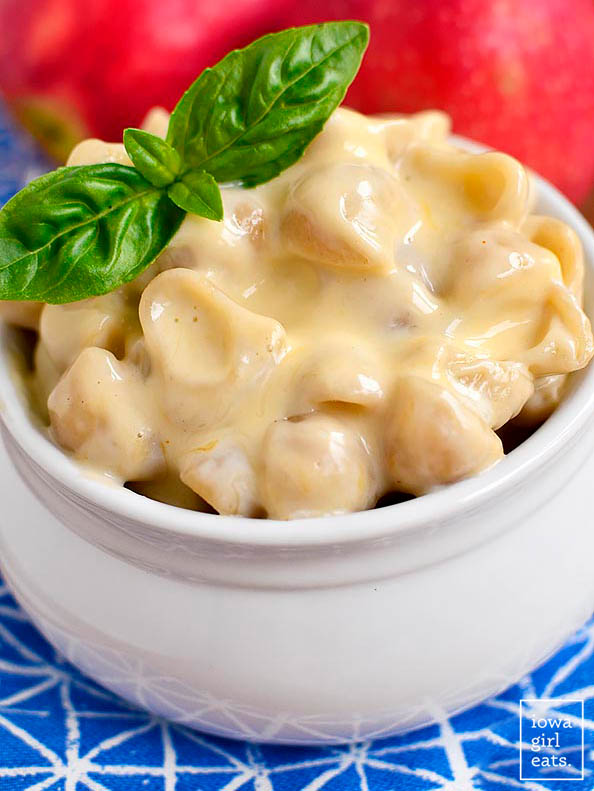 creamy gluten free mac and cheese in a bowl with a basil garnish