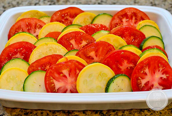 zucchini and summer squash layered with tomatoes in a baking dish