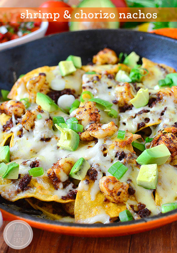 shrimp and chorizo nachos in a skillet with toppings