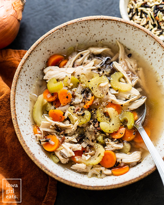 bowl of crock pot chicken and wild rice soup with a spon
