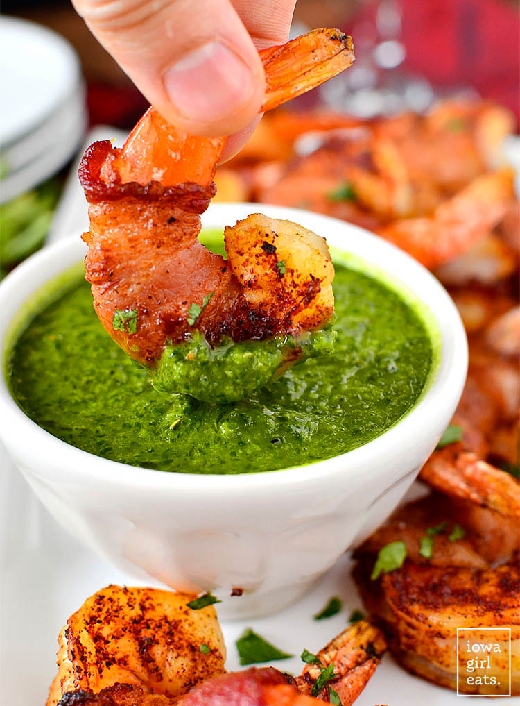 bacon wrapped bbq shrimp dunking in chimichurri sauce