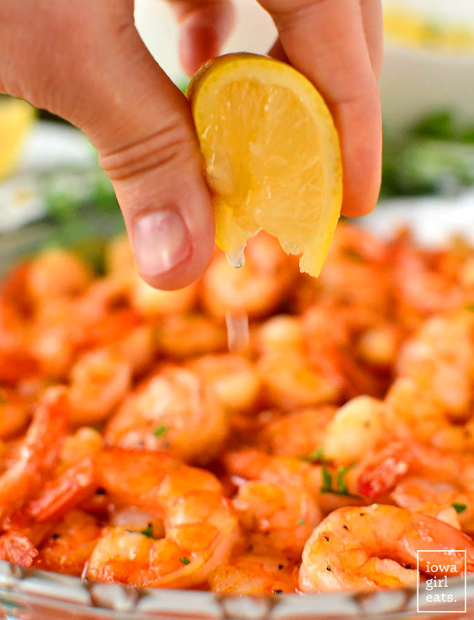 hand squeezing a lemon wedge on cajun shrimp