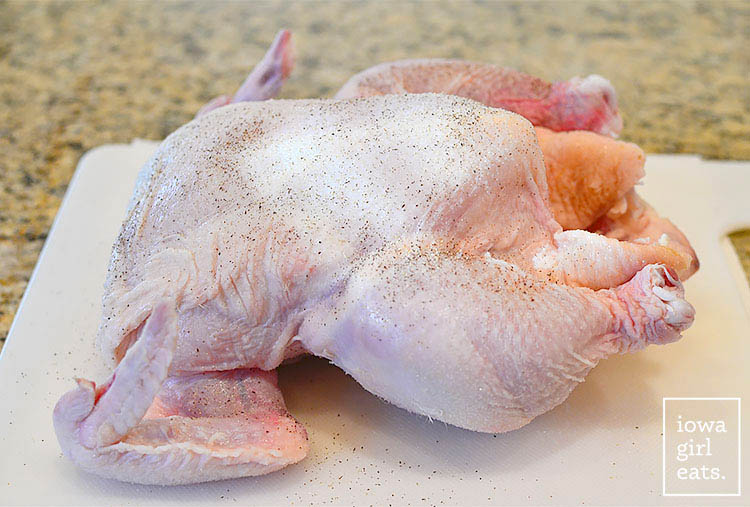 whole chicken seasoned with salt and pepper on a cutting board