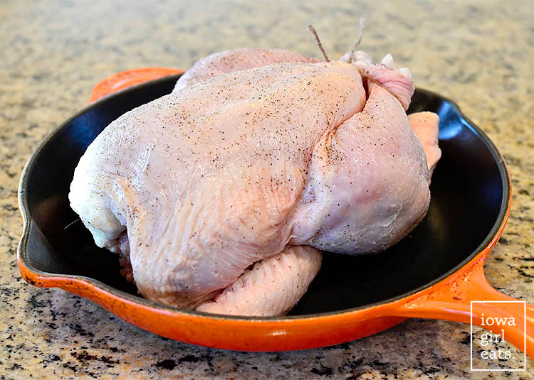 whole chicken seasoned with salt and pepper in a cast iron skillet