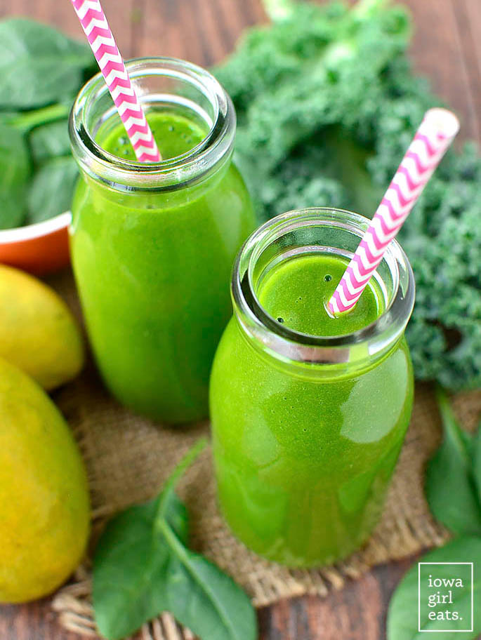 two mango spinach smoothies in glass jars with straws