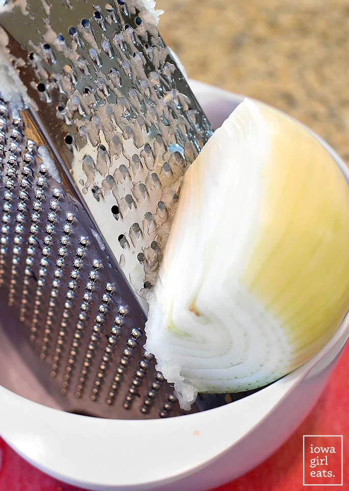 onion being grated on a box grater