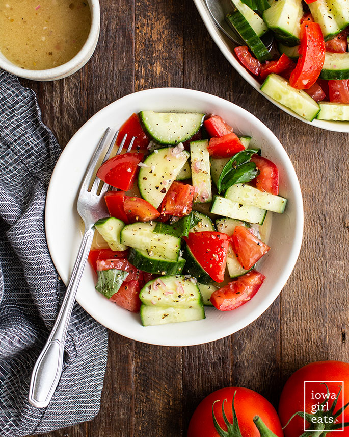 cucumber tomato salad with italian vinaigrette in a bowl with a fork