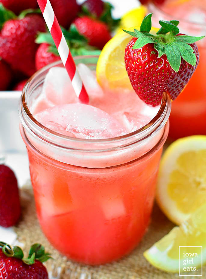 close up photo of a mason jar of strawberry lemonade over ice