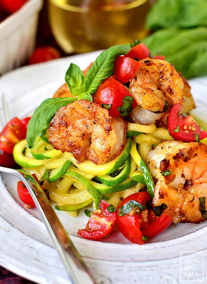 tomato basil shrimp with zoodles on a plate with a fork