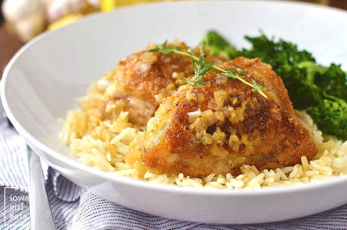 two pan roasted chicken thighs in a serving dish with rice