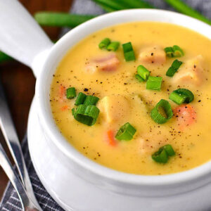cheesy ham and potato soup in a bowl with sliced green onions