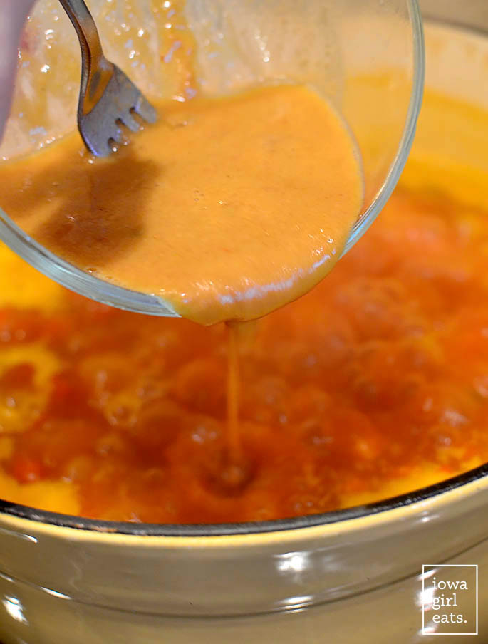 peanut butter being added to a pot of soup