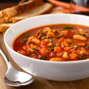 italian sausage spinach and tomato soup in a bowl with a spoon