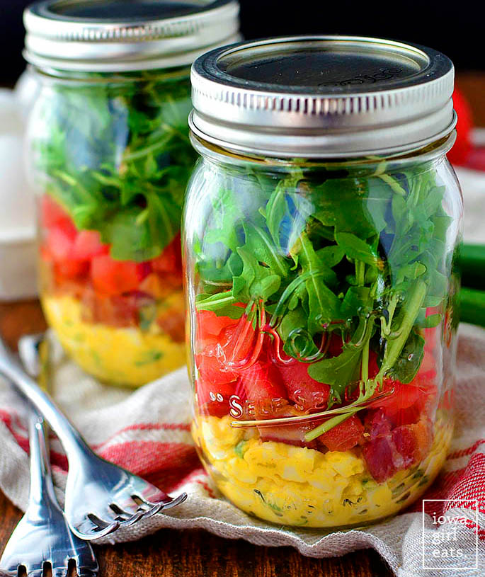 two mason jars with layered BLT salads in them