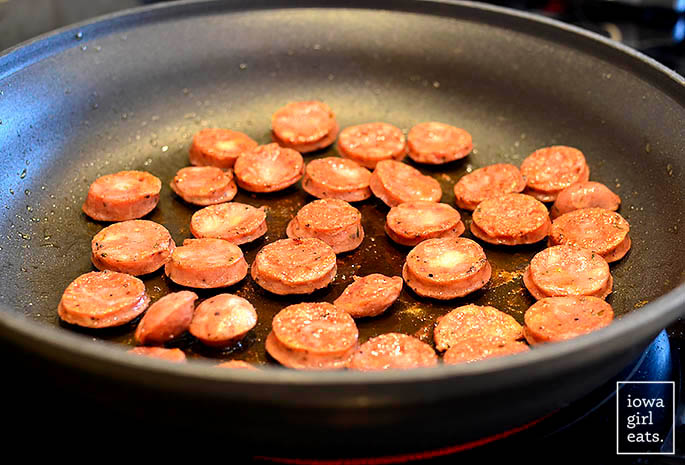 slices of chicken sausage sauting in a skillet