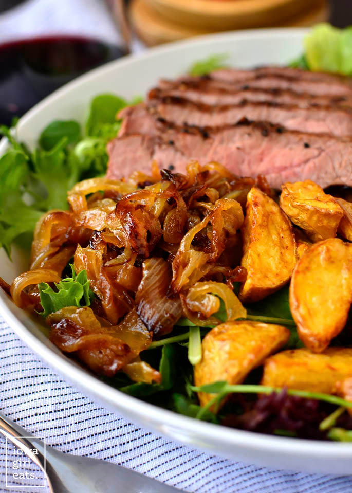 caramelized onions and potatoes on a steak salad