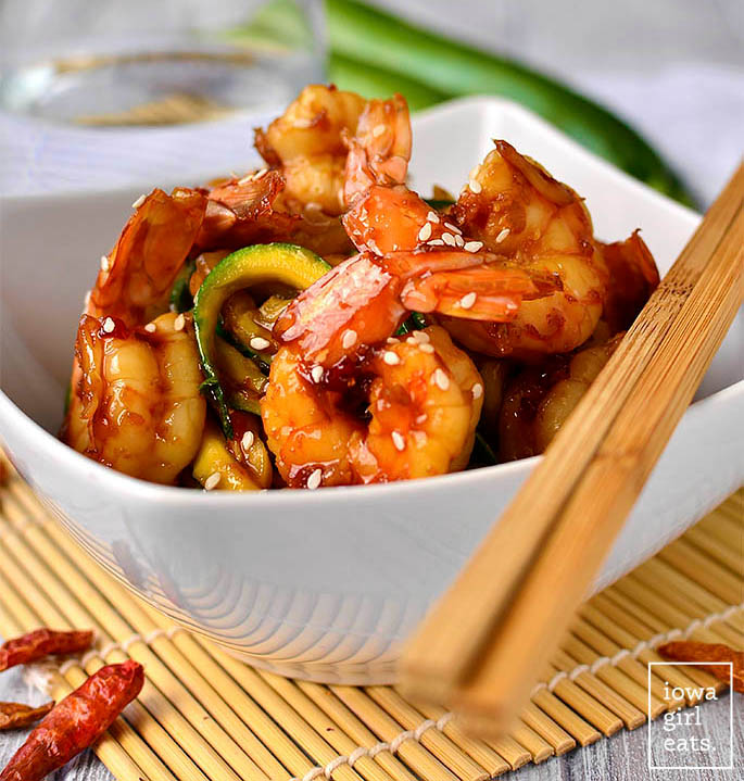 sweet chili sesame shrimp and zoodles in a bowl with chopsticks