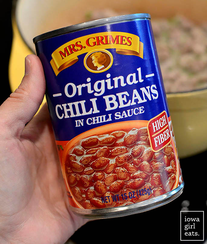 a hand holding a can of mrs grimes chili beans