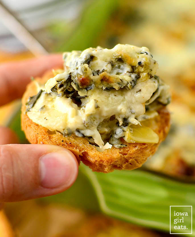 caesar spinach and artichoke dip on top of a crostini
