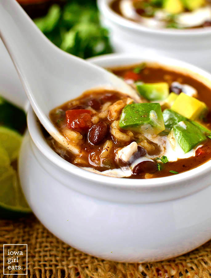a white spoon digging into a bowl of slow cooker black bean soup