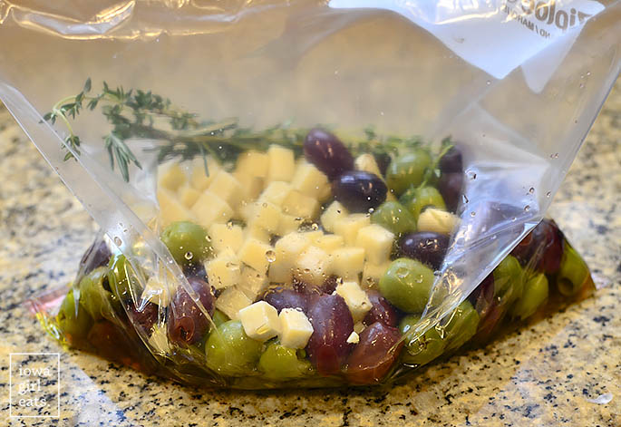 Closed Ziplock bag of olives, cheese, and herbs.
