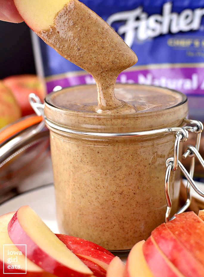 An apple slice dipped into almond butter.
