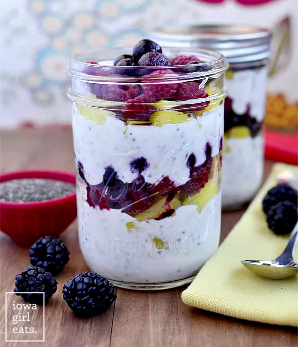 a jar of make ahead breakfast parfaits with fresh berries and a spoon