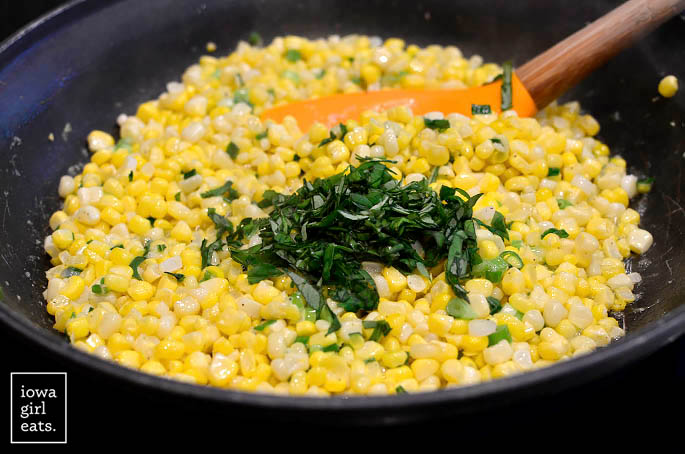 sweet corn sauting with garlic basil and butter in a skillet
