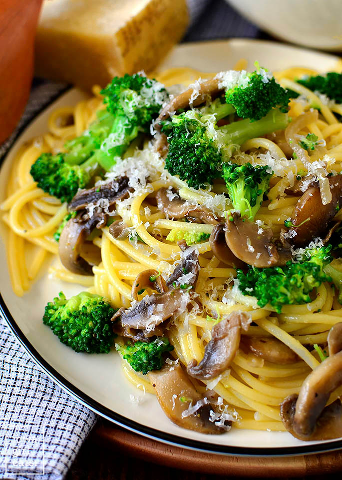 close up view of mushroom parmesan pasta with broccoli on a plate