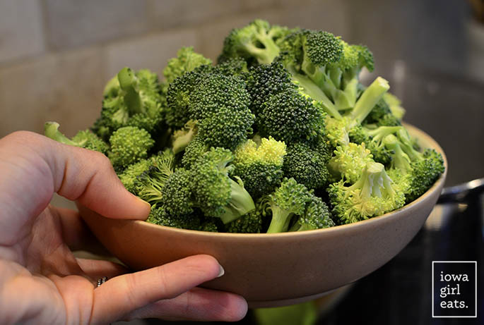 fresh broccoli florets going into a pot of water