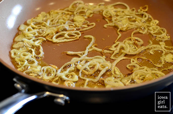 thinly sliced shallots pan frying in a hot skillet