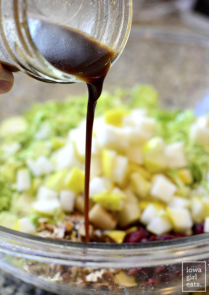 homemade maple dijon vinaigrette being drizzled over a shredded brussels sprouts salad