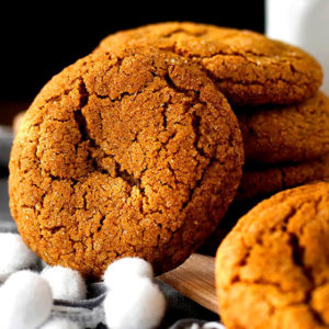 A Gluten Free Ginger Molasses Cookie propped against a stack of cookies.