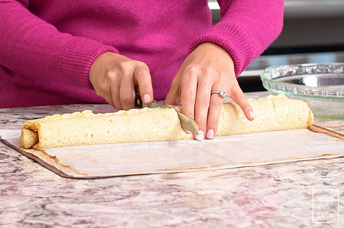 slicing a log of gluten free cinnamon roll dough