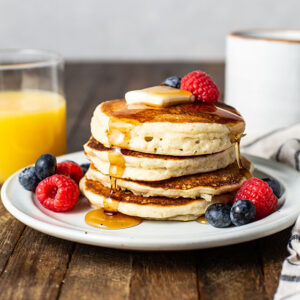 gluten free pancakes on a plate with syrup and berries