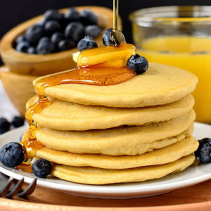 Stack of gluten free pancakes with butter, blueberries, and maple syrup