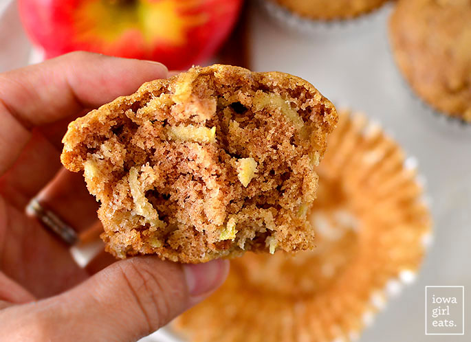 hand holding a gluten free apple cinnamon muffin with a bite taken out